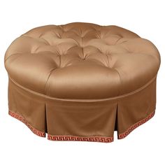 a round ottoman with an intricate design on the top and bottom, in tan leather