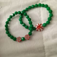 two green beads with candy canes are on a white sheet next to each other