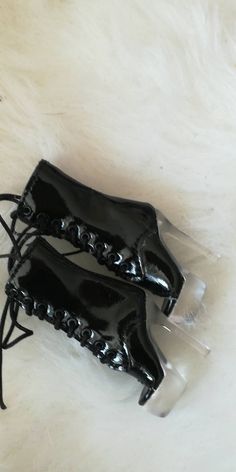 two black lace up boots sitting on top of a white fur covered floor