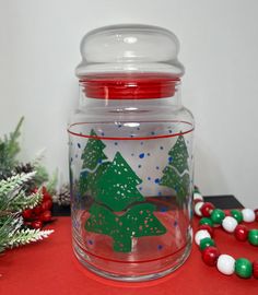 a glass jar sitting on top of a red table next to christmas decorations and candy