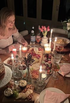 a woman sitting at a table with candles in front of her