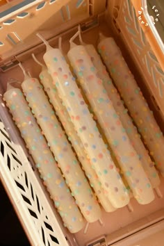 four candles are lined up in a box with confetti on them and sprinkles