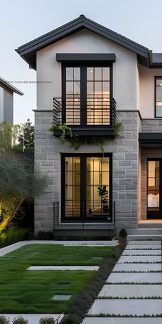 a modern house with stone steps leading up to the front door and windows on each side