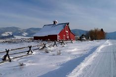 a red barn in the middle of a snowy field