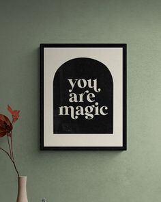 a black and white poster with the words you are magic hanging on a green wall