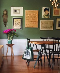 a dining room with green walls and pictures on the wall