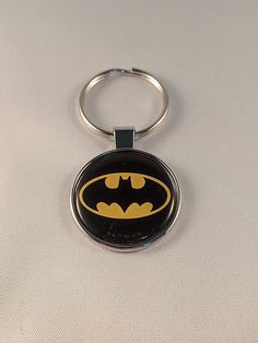 a batman keychain is shown on a white surface with a black and yellow logo