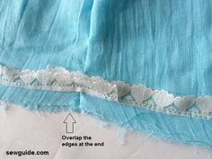 the edge of a piece of blue fabric with white lace on it and an arrow pointing up