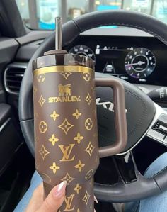 a person holding a cup in their hand while sitting in a car with the steering wheel behind them