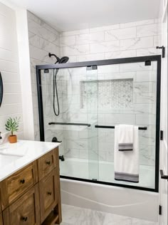 a bathroom with a sink, mirror and shower in it's center area that has marble tiles on the walls