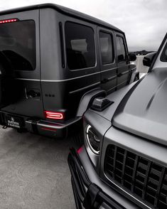 the back end of a black mercedes g - class parked in a parking lot next to other vehicles