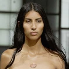 a woman with no shirt on walking down the runway