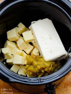 cubes of butter, onions and cheese in a crock pot on a wooden table