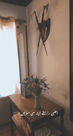 a vase with flowers sitting on a table in front of a wall clock and window