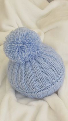 a blue knitted hat laying on top of a white blanket