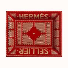 a red and white plate with the words hermess in arabic writing on it, against a white background