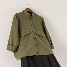 a green jacket hanging on a white wall next to a black and gray dress skirt