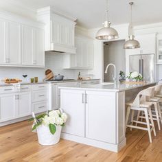 a large kitchen with white cabinets and wooden flooring, along with an island in the middle