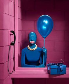 a blue mannequin in a pink room with a balloon