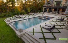 an outdoor swimming pool surrounded by grass and stone steps, with lounge chairs around it