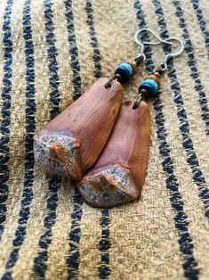 two pieces of wood with beads hanging from them on a striped tablecloth surface,