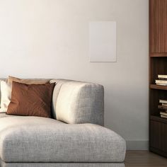 a white couch sitting in front of a book shelf next to a wooden cabinet with books on it