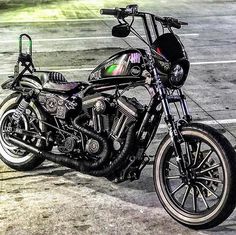 a black motorcycle parked in a parking lot next to another bike on the ground with no one around it