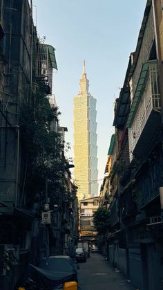 an alley way with cars and buildings in the background at sunset or sunrise, there is a yellow taxi cab parked on the street