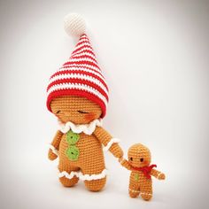 a small crocheted ginger holding the hand of a smaller one with a red and white striped hat