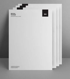 five white papers stacked on top of each other in front of a gray wall with black letters