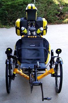 a yellow and black bicycle parked on top of a cement road next to grass covered hillside