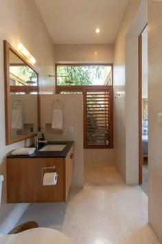 a bathroom with a sink, mirror and toilet in it next to a window that looks out onto the outdoors