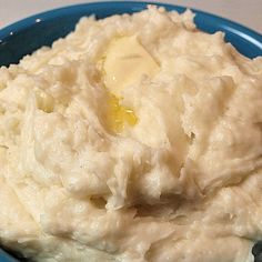 a blue plate topped with mashed potatoes covered in gravy next to a fork