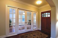 an empty room with two doors and a rug on the floor in front of it