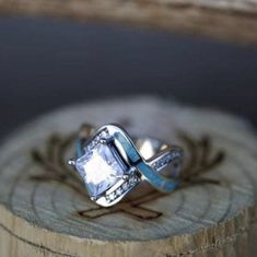 an engagement ring sitting on top of a piece of wood