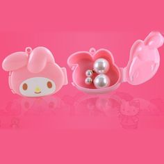 two hello kitty containers with pearls in them on a pink background, one has an earring and the other has a bow