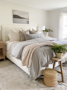 a bedroom with a bed, nightstands and plants in the corner on the floor