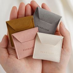 three small envelopes are in the palm of someone's hand, one has a card holder