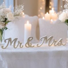 two vases filled with flowers and candles on top of a white cloth covered table