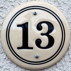 a white and black sign with the number thirteen in it's center is shown