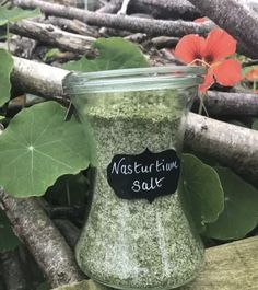 a jar filled with green stuff sitting on top of a wooden table next to leaves