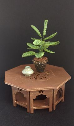 a small potted plant sitting on top of a wooden table next to a vase