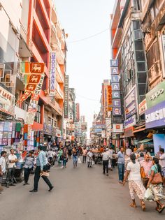 many people are walking down the street in front of stores and buildings with signs on them