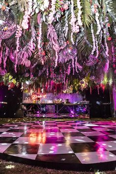 a dance floor with lights and flowers hanging from it's ceiling in front of a stage