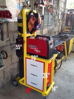 a yellow and red cart sitting next to a wall with tools on top of it