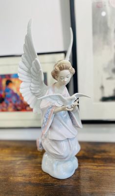 an angel figurine sitting on top of a table next to a framed photo