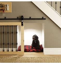 a black dog sitting on top of a bed under a stair case