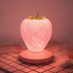 a strawberry shaped light sitting on top of a white tiled floor next to a book