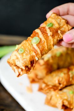 a person is holding up some food on a white plate with green onions and cheese