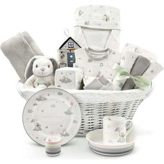 a white basket filled with baby items on top of a table next to a cup and saucer